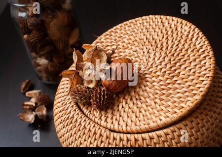 wicker scatola di paglia artigianale top rotondo con fiori secchi e lavanda su sfondo nero Foto Stock