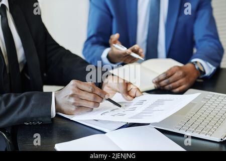 Primo piano di un uomo d'affari irriconoscibile che analizza i dati report in riunione e puntando a grafici finanziari, spazio copia Foto Stock