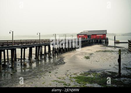 Vista da Coupéville Washington sull'Isola di Whidbey con molo e edificio storico in vista, in una giornata piovosa Foto Stock
