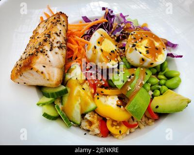 Un salmone alla griglia con uova sode, avocado, lattuga, piselli, pomodori e carote Foto Stock