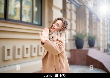 donna cammina sulla strada della città e ondeggiando Arrivederci o Ciao. donna mano gesto saluto o bye Foto Stock