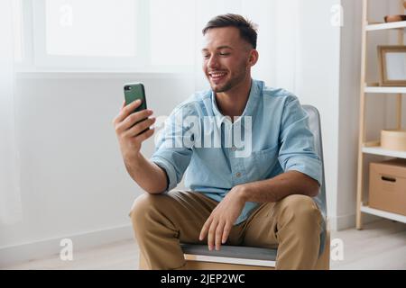 Felice carino gioioso parlare con un amico utilizzando telefono videochiamata discute le ultime notizie piacevole sollevare sorrisi guarda lo schermo. Comunicazione a distanza Foto Stock