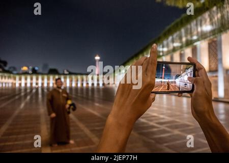 Jakarta, Indonesia. 17th giugno 2022. I congreganti della moschea Istiqlal si alternano scattando foto per catturare la bellezza della moschea di notte. L'atmosfera della città di Giacarta, Indonesia di notte, che è così affollata con varie attività. Credit: SOPA Images Limited/Alamy Live News Foto Stock