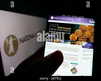 Persona che tiene il cellulare con la pagina web della National Academy of Sciences (NAS) sullo schermo di fronte al logo. Concentrarsi sul centro del display del telefono. Foto Stock