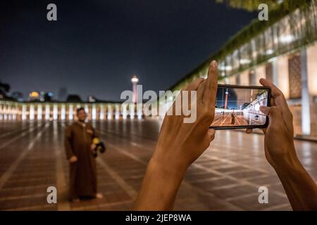 Jakarta, Indonesia. 17th giugno 2022. I congreganti della moschea Istiqlal si alternano scattando foto per catturare la bellezza della moschea di notte. L'atmosfera della città di Giacarta, Indonesia di notte, che è così affollata con varie attività. (Credit Image: © Andry Denisah/SOPA Images via ZUMA Press Wire) Foto Stock