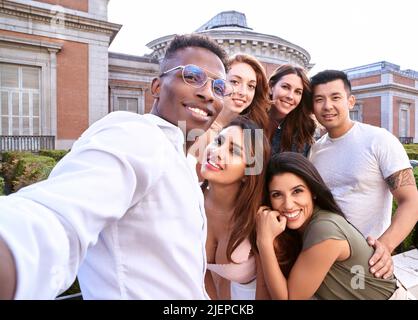 Gruppo di amici multirazziali sorridenti mentre si prende un selfie insieme all'aperto. Concetto di amicizia e unità. Foto Stock