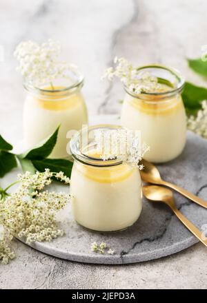 Delizioso dessert italiano di fiori di sambuco, panna cotta con salsa di limone e fiori freschi in vasetti di vetro. Concetto di cibo biologico fatto in casa. Foto Stock