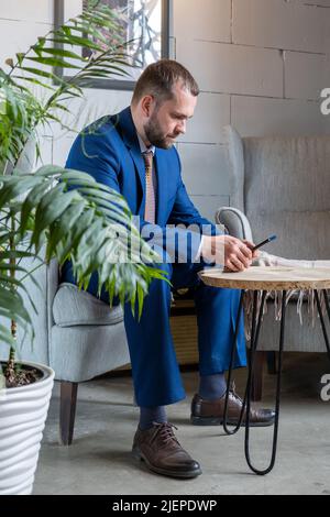 Mediocre uomo d'affari arabo freelancer utilizzando il telefono cellulare controllare i feed dei social media o messaggi di chat mentre si siede in bar Foto Stock