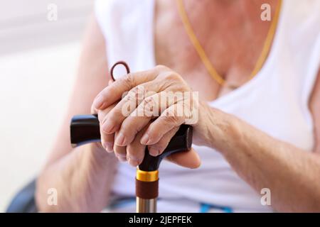 Mani di una vecchia donna sul primo piano di canna Foto Stock