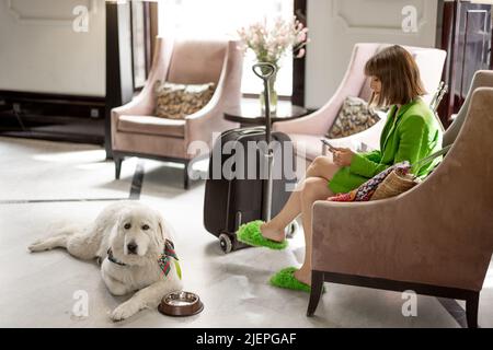 Donna d'affari con cane nella hall dell'hotel Foto Stock