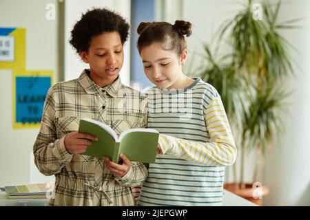 Vita ritratto di due ragazze rispondere domande a scuola di fronte alla classe e tenere un libro Foto Stock