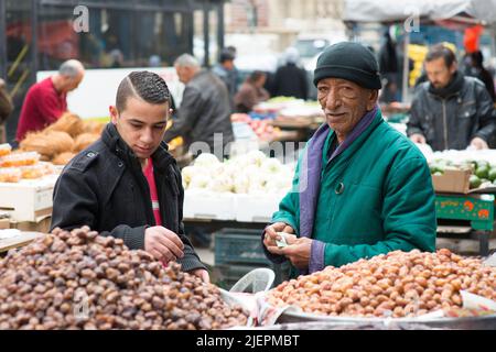 Amman, Giordania. Un mercante Jordanian Market, che in precedenza lavorava all'interno del porto di Rotterdam, vendendo frutta, verdura e ingredienti alimentari in un mercato alimentare del centro città, attirando molti clienti. Foto Stock