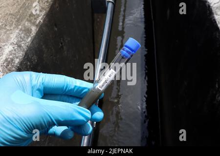 Prelevare i campioni di acque reflue dai canali industriali in provette da esaminare in laboratorio Foto Stock