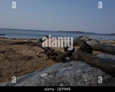 Catena di metallo adagiata sulla sabbia sulla spiaggia. Foto Stock