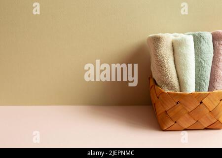 Asciugamani in cestello su tavolo rosa. Parete di fondo beige Foto Stock