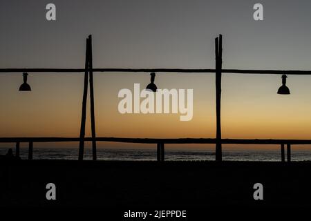 Una silhouette di un molo di legno con lampade pendenti al tramonto a Swakopmund, Namibia Foto Stock