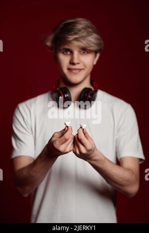 il giovane uomo in t-shirt bianca dona cuffie moderne Foto Stock