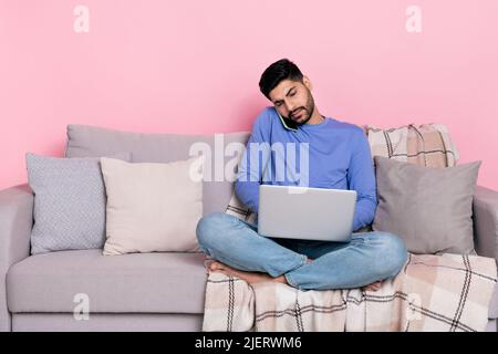 Foto di serio occupato uomo arabo indossare camicia manica lunga seduta divano scadenza lavoro gadget spazio vuoto isolato colore rosa sfondo Foto Stock