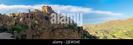Vista serale del villaggio disabitato di Gamsutl sulla cima di una montagna a Dagestan, il villaggio abitato di Chokh è visibile in lontananza Foto Stock