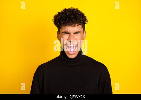 Foto di irritato pelle scura uomo indossare nero jumper urlando occhi chiusi isolato colore giallo sfondo Foto Stock
