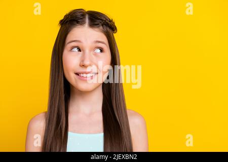 Foto di sognante mente felice ragazza piccola sguardo spazio vuoto buon umore isolato su sfondo giallo Foto Stock