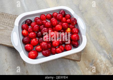 Prugne di ciliegia rossa mature sul piatto. Frutta succosa su sfondo di legno, primo piano. Susina fresca, cibo vegetariano Foto Stock