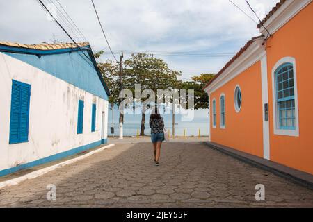 Giovane donna che cammina in una strada caratteristica, con accesso al mare, nella città di Ribeirão da Ilha, Brasile. Foto Stock