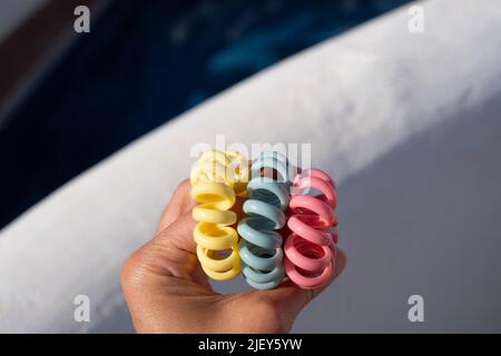 La spirale in plastica scrunchies la fascia dei capelli nella mano. Fasce colorate a spirale per capelli Foto Stock