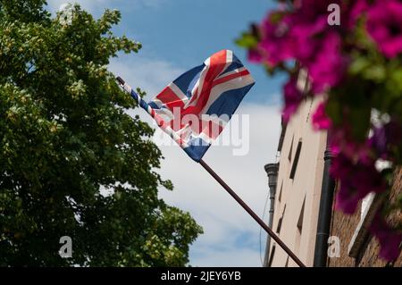 union jack che vola in brezza su palo attraverso i fiori Foto Stock