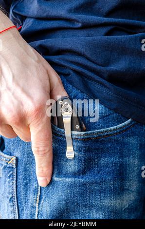 L'uomo ha le mani nei guanti che tengono il coltello Foto Stock