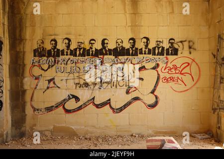 Graffiti politici spruzzati su un muro di pietra arenaria di una proprietà domestica vandalizzata e disastata, Gozo Foto Stock