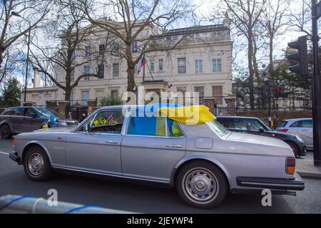 Un’auto con bandiere ucraine corre per protestare contro l’invasione dell’Ucraina da parte della Russia nei pressi dell’ambasciata russa a Londra. Foto Stock