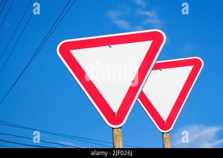 Segnaletica stradale rossa isolata. Sfocare due cartelli stradali vuoti rossi a triangolo con sfondo blu cielo. Direzione di pericolo. Fuori fuoco. Foto Stock