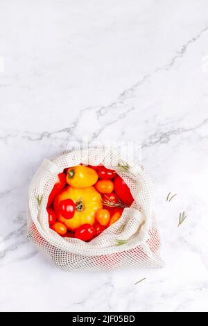 diverse varietà di pomodori e peperoni in una borsa riutilizzabile in cotone, raccolta di verdure estive, concetto zero rifiuti, vista dall'alto, spazio copia Foto Stock