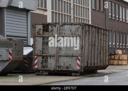 Grande contenitore grigio per rifiuti (dumpster) davanti a un edificio industriale Foto Stock