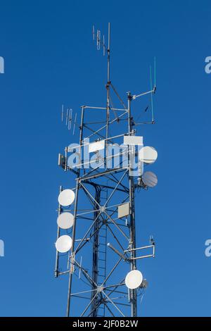 Una torre di comunicazione contro un cielo blu Foto Stock