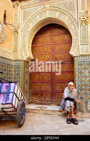 Marocco Fez. Un uomo maturo seduto alla porta di un edificio storico nella Medina Foto Stock