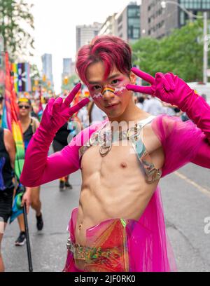 Colpo medio di un giovane uomo che indossa palco marciando su misura di fronte a un gruppo durante la Pride Parade Foto Stock