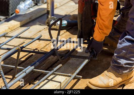 Attrezzo di legatura per armature utilizzato dai lavoratori edili per fissare le barre di acciaio con le barre metalliche per rinforzare il cemento Foto Stock