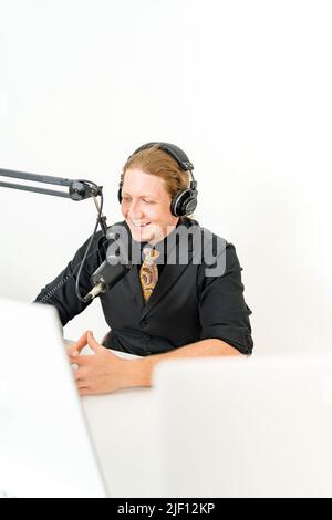 Uomo che sorride davanti al microfono indossando le cuffie Foto Stock