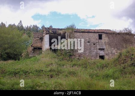 questa vecchia casa in pietra abbandonata in campagna è un caos totale e guardarla causa una sensazione di tristezza Foto Stock