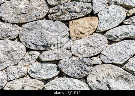 Parete di pietra ruvida come texture di sfondo creativa. Pietre naturali muratura con cuciture irregolari. Sfondo muro di pietra Foto Stock