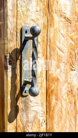 Maniglia della porta forgiata a mano sulla porta in legno da vicino Foto Stock