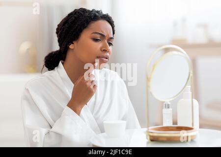 Frustrata Donna Nera con problema pelle guardando pimple su Cheen Foto Stock