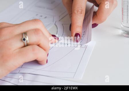 Donna su misura durante il lavoro su modelli di cucitura. Unire i dettagli della carta per vestire Foto Stock