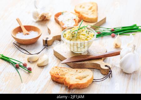 Burro all'aglio fatto in casa con erbe e erba cipollina e baguette appena tostata con sale Foto Stock