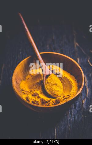 Curcuma in polvere indiana, curcuma in ciotola piccola con cucchiaio, Haldi in polvere su sfondo di legno Foto Stock