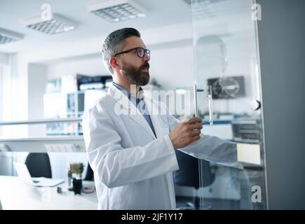 Un ingegnere di robotica che lavora alla progettazione di moderni bracci robotici in laboratorio. Foto Stock