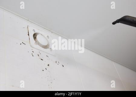 Un uomo pulisce la polvere da un tecnico della griglia di ventilazione pulendo l'aria Foto Stock