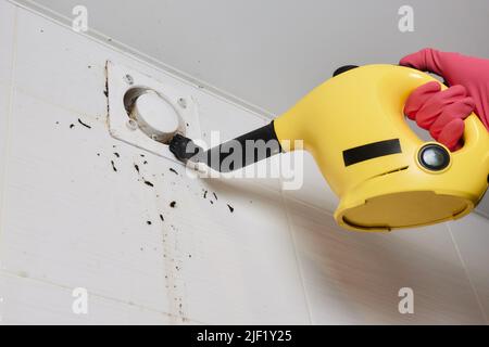 Un uomo pulisce la polvere da un tecnico della griglia di ventilazione pulendo l'aria Foto Stock